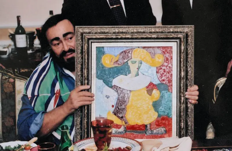 Luciano Pavarotti holding a painting by Igor Tcholaria